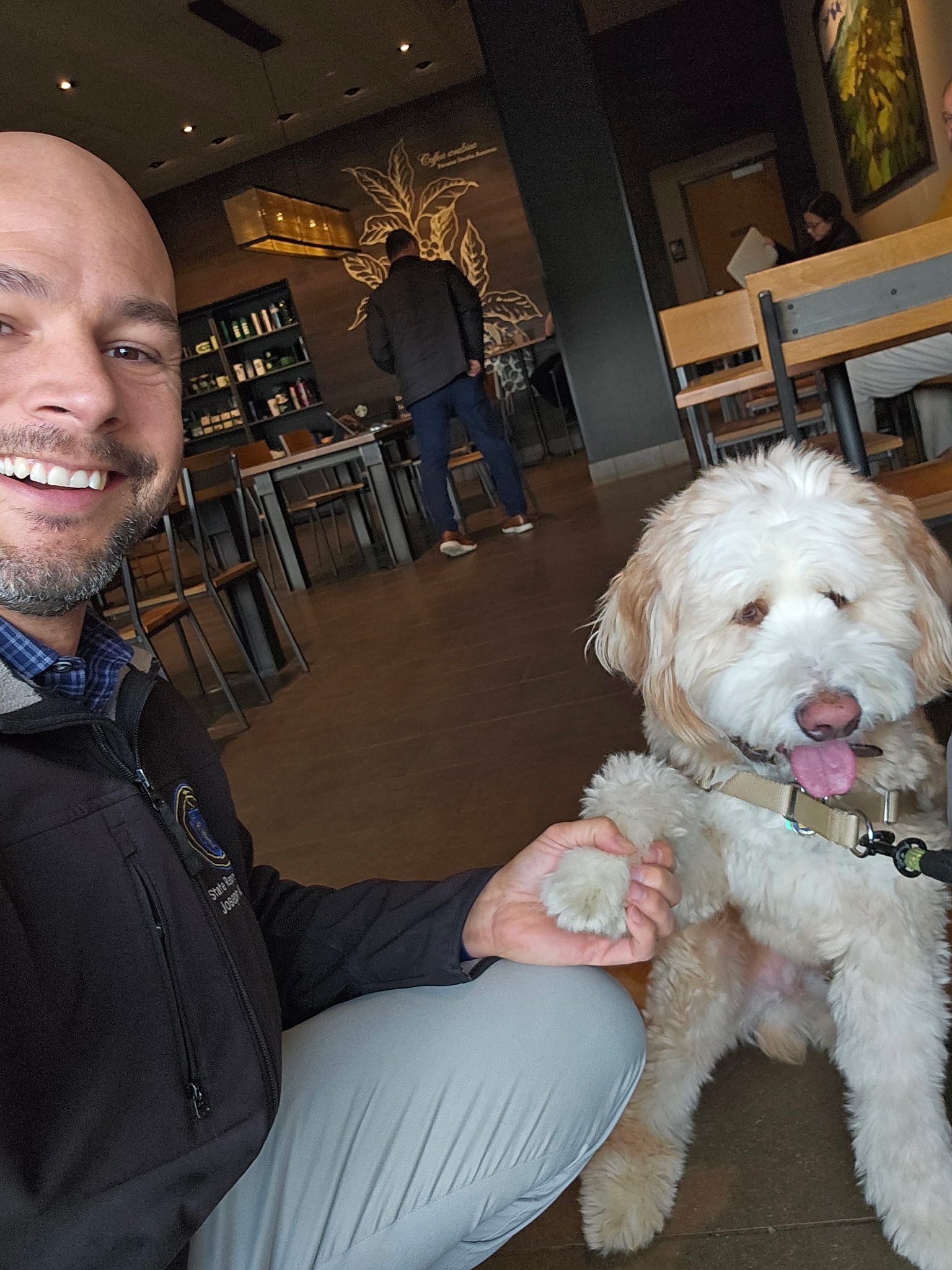 Joe McKenna with a fluffy goldendoodle at a coffee shop